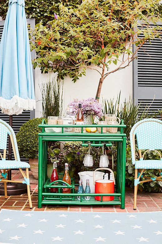 For entertaining alfresco, a bar cart can hold not only beverages, drinkware, and ice but also barbecue condiments, cutlery, and napkins. Find the patio umbrella here; find similar chairs here. Photo by Joe Schmelzer.
